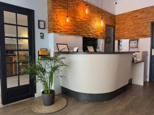 a restaurant with a counter with a potted plant at L'Hôtel Bristol in Caen