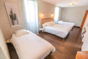 Dos camas en una habitación pequeña con sábanas blancas. en Gîte Ainerak, en Sainte Engrace 17 fotos más