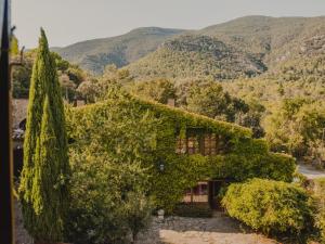 Ein mit Efeu bewachsenes Haus vor dem Hintergrund der Berge in der Unterkunft Off Grid Girona in Beuda