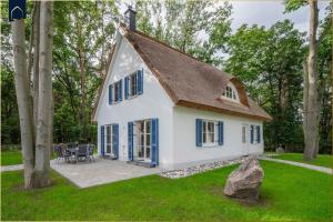 a small white house with blue windows and a yard at Fischerdorf Ferienhaus Im Kiefernwäldchen in Zirchow