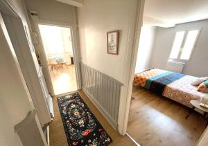 a bedroom with a bed and a hallway with a rug at L'Erable - Calme en Plein centre - 1er étage in Auch +4 photos