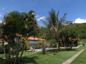 a resort with palm trees and a swimming pool at Pousada Recanto do João de Barro in Conservatória