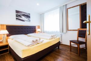 a bedroom with a bed and a chair and a window at Old Town City Center Apartment Post in Zell am See
