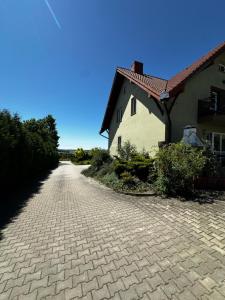 a brick road next to a house with a roof at Przy Kamieńcu in Krajno Pierwsze