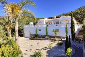 una casa blanca con palmeras delante en Cabana do Monte, en Santa Bárbara de Nexe