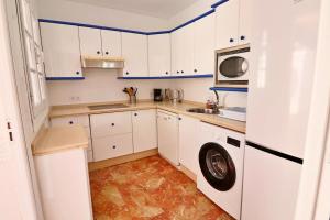 a kitchen with white cabinets and a washer and dryer at Antequera 49 in La Cala de Mijas