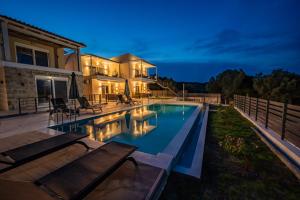 a swimming pool in front of a house at Anemos Luxury Home in Pogoniá