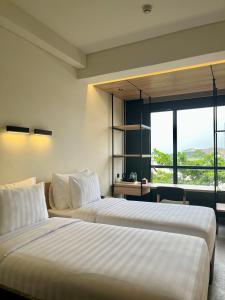 two beds in a room with a large window at ATOOI Hotel Alam Sutera in Serpong