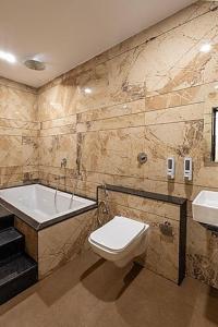 a bathroom with a tub and a toilet and a sink at Hotel Money Plant in Jogeshwāri