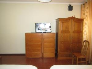 Habitación con TV en la parte superior de un armario de madera. en Apartamentos Valdemar, en Viana do Castelo