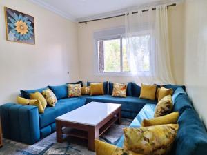 a living room with a blue couch and a table at Cool Family Apartment 2Chambres Balcon,WiFi,Tanger in Tangier