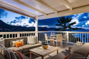 a porch with a couch and a table and chairs at Fresh Summer Villa with Superb View of the Hills in Quartier de Lorient