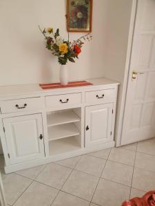 a white cabinet with a vase with flowers in it at Edit apartman in Zamárdi