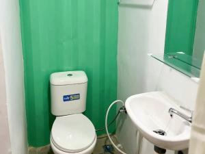 a green bathroom with a toilet and a sink at RedDoorz Syariah at Budget Guesthouse Sepaku in Sepaku