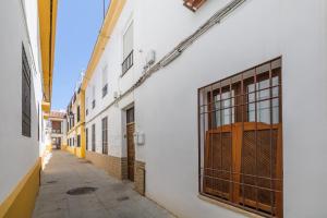 Une allée avec un bâtiment blanc et une fenêtre dans l'établissement Aromas de Especieros, à Cordoue