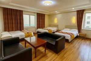 a hotel room with three beds and a couch at Evergreen Hotel in Ulaanbaatar