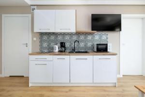 Una cocina blanca con gabinetes blancos y un microondas. en Nadmorski Apartament w Pobierowie z Parkingiem oraz Basenem by Noclegi Renters, en Pobierowo