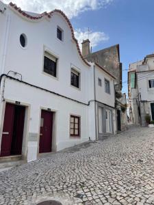a cobblestone street with a white building at Casa Eça in Sesimbra