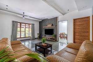a living room with a couch and a tv at Senaro Farms in Varagampadi