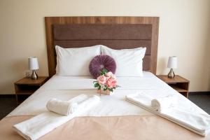 Family Suite One-Bedroom with Kitchen في ساينت قسطنطين وهيلينا: سرير مع منشفتين وباقة ورد