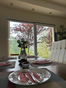 ein Esstisch mit Tellern und Besteck und ein Fenster in der Unterkunft Nihad B&B in Visoko