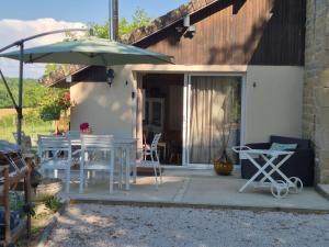 a patio with a table and chairs and an umbrella at A La Maison in Les Repôts