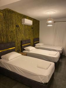 a room with three beds and a wall at Uyar Pansiyon & Apart in Bodrum City