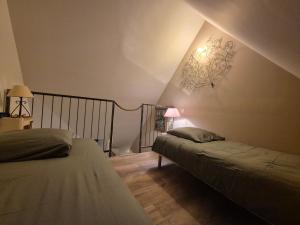 a attic bedroom with two beds and a chandelier at A La Maison in Les Repôts +4 photos