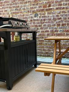 a grill and a bench next to a brick wall at Studio Malheux centre ville avec terrasse in Trouville-sur-Mer