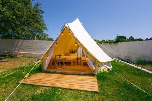 a yellow tent with a table in the grass at Kampaoh Rianxo in Rianjo