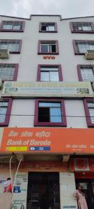 a tall white building with an orange sign on it at Hotel Four Square in Dīgha