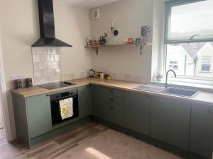 eine Küche mit grünen Schränken, einem Waschbecken und einem Fenster in der Unterkunft The Meads in Ilfracombe + 25 Fotos