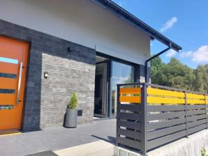 dom z pomarańczowymi drzwiami i płotem w obiekcie Przepiękny apartament ORANGE z widokiem na Skrzyczne - Sun&Sport w Szczyrku
