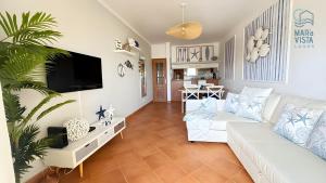 ein Wohnzimmer mit einem weißen Sofa und einem Fernseher in der Unterkunft Mar à Vista Lagos in Lagos