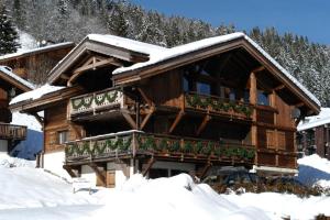a log cabin with snow on the roof at Chalet Elise des Alpes in Les Gets