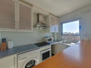 a kitchen with white cabinets and a sink and a dishwasher at Alquilaencanarias-Medano Los Martines beachfront A in El Médano