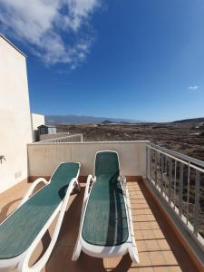 a balcony with two green and white chairs on it at Alquilaencanarias-Medano Los Martines beachfront A in El Médano