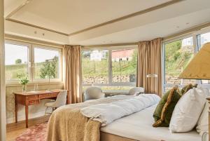 ein Schlafzimmer mit Bett, Schreibtisch und Fenstern in der Unterkunft Hotel Ullensvang in Lofthus