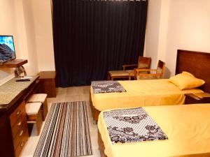 a hotel room with two beds and a table and chairs at قريه اكوا فيو الساحل الشمالى in El Alamein