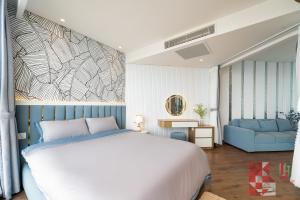 - une chambre avec un lit blanc et un canapé bleu dans l'établissement Apec Mandala Mui Ne by LHG - Sea View, Infinity Pool, 17m to Bàu Trắng Bình Thuận, à Mui Ne 44 autres photos