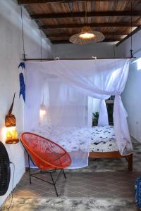 a bedroom with a bed and a red chair at Habitacion Tiburon Ballena - Casa Tortuga in El Valle