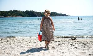 a young girl walking on the beach with a bucket at Strand Hotel Fevik - by Classic Norway Hotels in Grimstad
