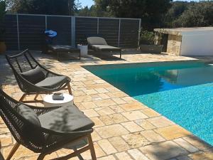 a swimming pool with chairs and a table next to it at Paxos Dream House in Vlachopoulátika