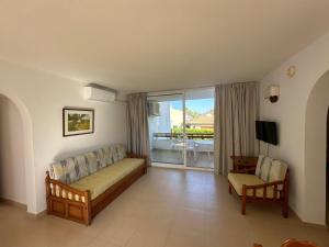 a living room with a couch and a balcony at Apartamentos Leo in Port de Pollensa
