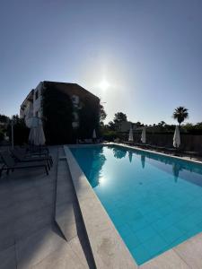 a swimming pool with chairs and umbrellas next to a building at Apartamentos Leo in Port de Pollensa