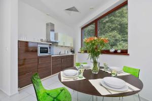 ein Esszimmer mit einem Tisch und grünen Stühlen in der Unterkunft Two-level Modern Apartment with Spacious Terrace - Ideal Place for the Holiday by Noclegi Renters in Wisełka