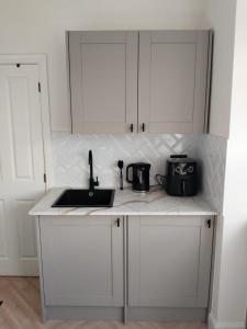 a kitchen with white cabinets and a sink at Donnybrook in Streatham Vale