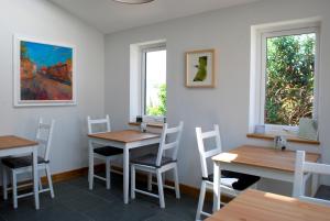 a dining room with two tables and two windows at Ty Boia Bed & Breakfast in St. Davids