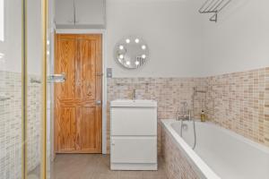 a bathroom with a tub and a sink and a wooden door at Reading Station - Modern Home with its own Garden Sleeps 6 in Reading