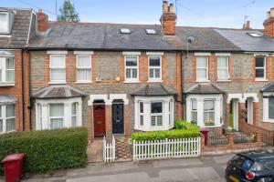 a brick house with a red door and a white fence at Reading Station - Modern Home with its own Garden Sleeps 6 in Reading